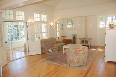 a living room filled with furniture and lots of windows on top of wooden flooring