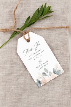 a tag tied to a piece of linen with flowers on it that says thank you