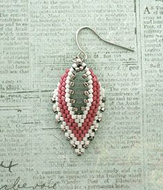 a pair of red and white beaded earrings sitting on top of a piece of paper