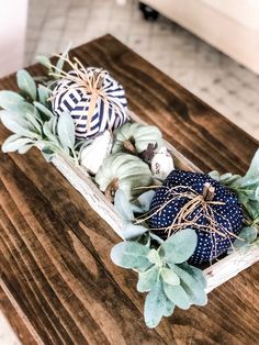 a wooden table topped with blue and white pumpkins next to greenery on top of it