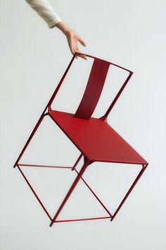 a person is reaching for a chair that has been folded in the shape of a cube