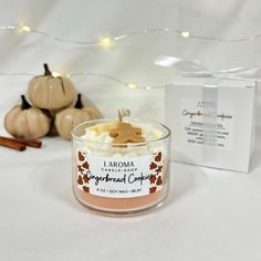 a small glass jar filled with whipped cream next to some pumpkins and cinnamon sticks