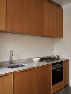 a kitchen with wooden cabinets and a white bowl on the counter top next to an oven