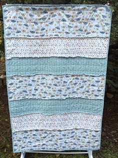 a blue and white quilt hanging from the side of a wooden stand in front of some trees