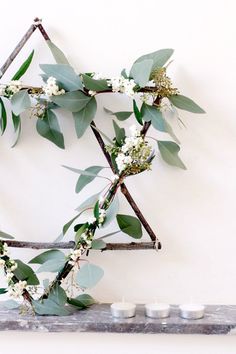 branches with white flowers and green leaves on them are arranged in the shape of an x