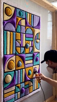 a man is using a blow dryer to paint a colorful art piece on the wall