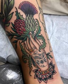 a woman's arm with tattoos on it and flowers in the middle of her arm