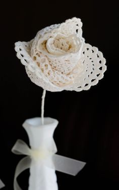 a white vase with a flower in it on a black tablecloth and ribbon tied around the base