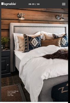 a bed with white linens and pillows in a room that has wood paneling on the walls