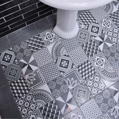 a bathroom with black and white tiles on the floor, sink and toilet in it