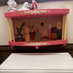 a pink shelf filled with bottles next to a dryer