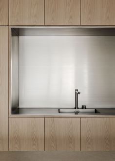 a stainless steel kitchen sink in front of a wooden cabinet and countertop with two faucets on each side