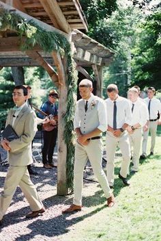 a group of men walking down a road next to each other under a wooden structure