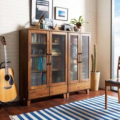 a room with a bookcase, guitar and potted plant on the floor next to it