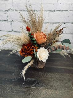 an arrangement of dried flowers and foliage on a wooden table