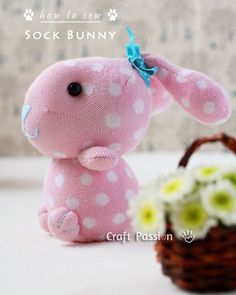 a pink stuffed animal sitting next to a basket with flowers and a small white flower