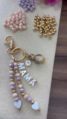 some beads and charms are laying on a table next to each other with the word mama spelled in white letters