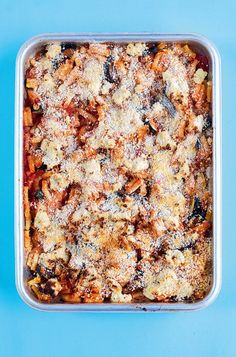 a casserole dish with meat and vegetables in it on a blue table top