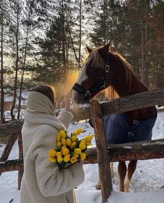 a woman is petting a horse on the nose and holding flowers in her hand