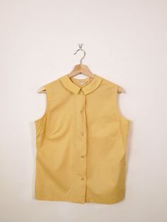 Vintage 1960s Mellow Yellow Sleeveless Blouse/Women's Shirt. Measurements Length: 23" Armpit to armpit : 19 1/2" Shoulder: 14 1/2" Condition: Gently used. There's no stains or holes. Good condition.  ※Please read the policy before you purchase※ Affordable Vintage Yellow Shirt, Cheap Yellow Vintage Blouse, Yellow Sleeveless Vest For Work, Vintage Yellow Sleeveless Top, Classic Tops For Vintage Fashion, Vintage Sleeveless Tank Top For Spring, Retro Sleeveless Vest Top, Vintage Sleeveless Blouse For Spring, Vintage Sleeveless Tops For Daywear