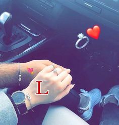 a man and woman holding hands while sitting in the drivers seat of a car with an i love you sign on the dash board