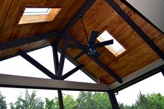 a ceiling fan in the middle of a room with wood paneling and glass walls