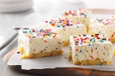 several pieces of cake with sprinkles are on a wooden platter and ready to be eaten