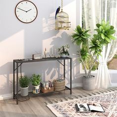 a living room with plants and a clock on the wall next to a table that has a birdcage hanging from it