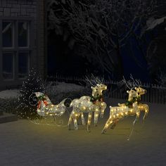 three lighted reindeers in front of a house