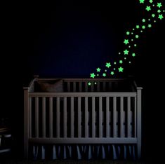 a baby crib with green stars on the wall and in the background is a night sky