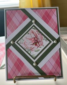 a close up of a card on a table with pink and green checkered paper