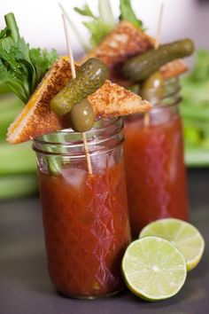 two mason jars filled with pickles and garnish on top of a table