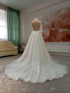 the back of a wedding dress on display in a room with a couch and large window