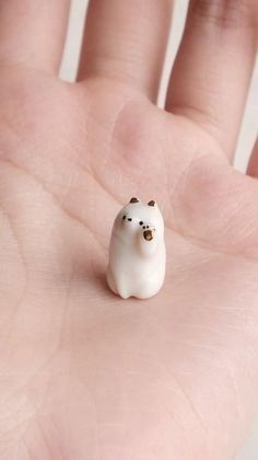 a tiny white bear sitting on top of a persons hand