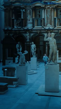 several statues on pedestals in front of a building