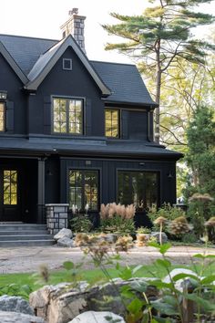 a large black house with lots of windows and plants in front of the door area