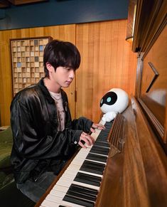 a man sitting at a piano playing an electronic keyboard with a stuffed animal on top of it