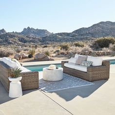 two wicker couches sitting on top of a patio next to a swimming pool