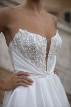 a woman in a white wedding dress with her hands on her hips, posing for the camera