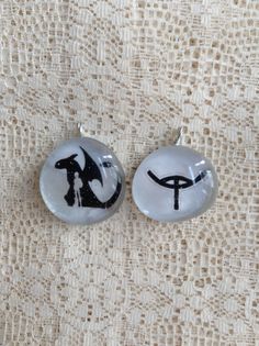 two glass cabochons with black and white designs on them sitting on a table