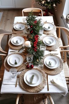 the table is set for christmas dinner with white plates and silverware