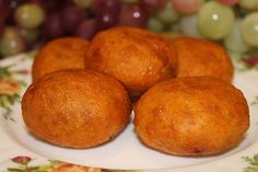 four round pastries on a plate with grapes in the background