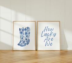 two blue and white prints with the words how lucky are we on them in front of a wooden floor