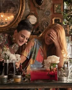 two people sitting at a table with flowers