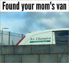 a white truck driving down a road next to a cement wall with a sign on it