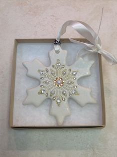 a snowflake ornament in a box with a ribbon on the side