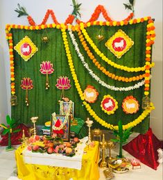 a table topped with lots of food next to a green wall covered in flowers and decorations