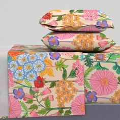 three pillows stacked on top of each other with colorful flowers and leaves printed on them