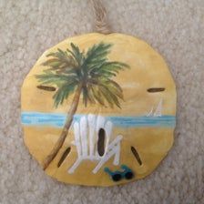 a wooden ornament with a palm tree and beach scene painted on it's side