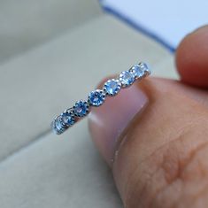 a close up of a person's hand holding a ring with blue stones on it